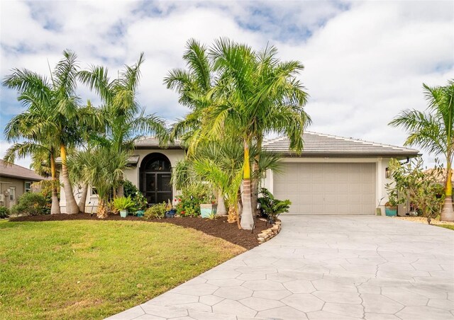 view of front of home with an attached garage, concrete driveway, a tiled roof, stucco siding, and a front yard