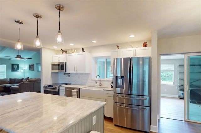 kitchen with appliances with stainless steel finishes, light hardwood / wood-style floors, white cabinetry, and ceiling fan