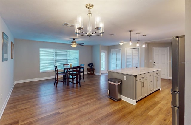 kitchen featuring a center island, decorative light fixtures, ceiling fan with notable chandelier, white cabinetry, and stainless steel fridge