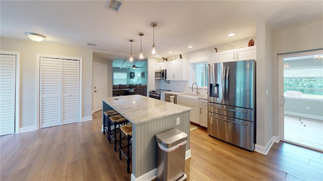 kitchen featuring a kitchen island, hanging light fixtures, appliances with stainless steel finishes, and white cabinets