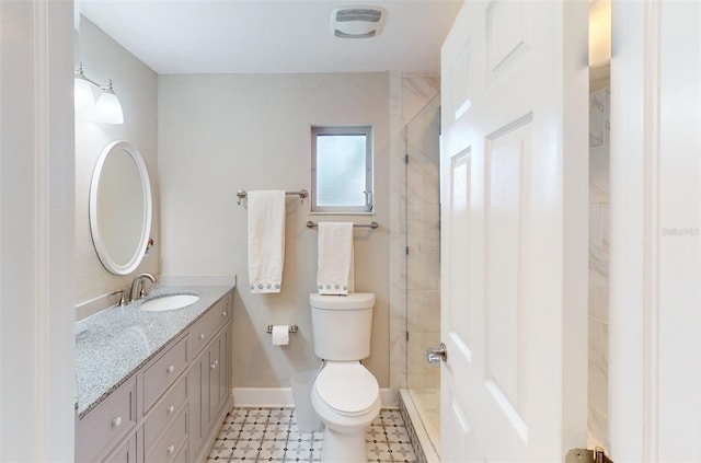 bathroom with toilet, a tile shower, and vanity