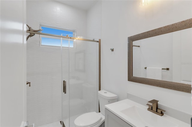 bathroom with vanity, a shower with door, and toilet