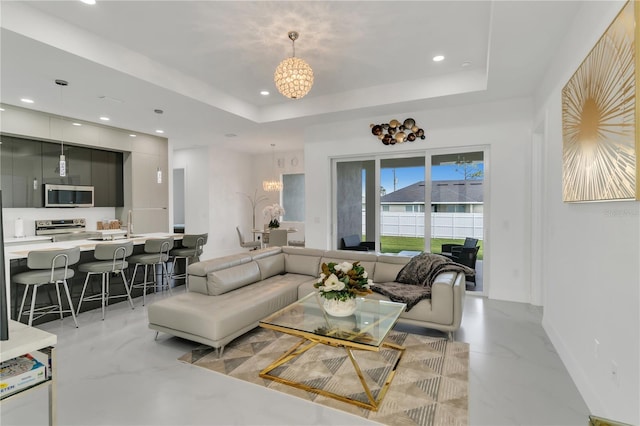 living room featuring a raised ceiling and a notable chandelier