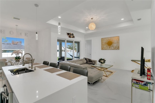 living room featuring a raised ceiling, plenty of natural light, and sink