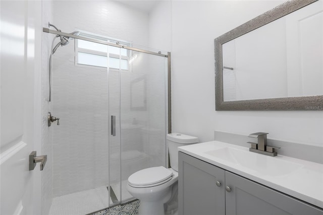 bathroom featuring vanity, a shower with shower door, and toilet