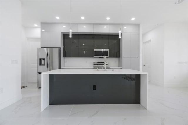 kitchen with pendant lighting, an island with sink, sink, white cabinets, and stainless steel appliances