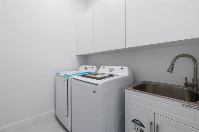 clothes washing area featuring sink, washing machine and dryer, and cabinets