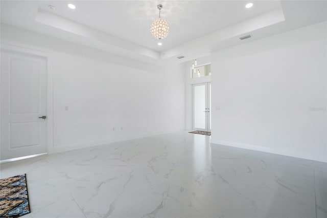 empty room with a notable chandelier and a tray ceiling