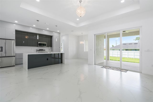 kitchen with a notable chandelier, hanging light fixtures, a tray ceiling, and stainless steel appliances