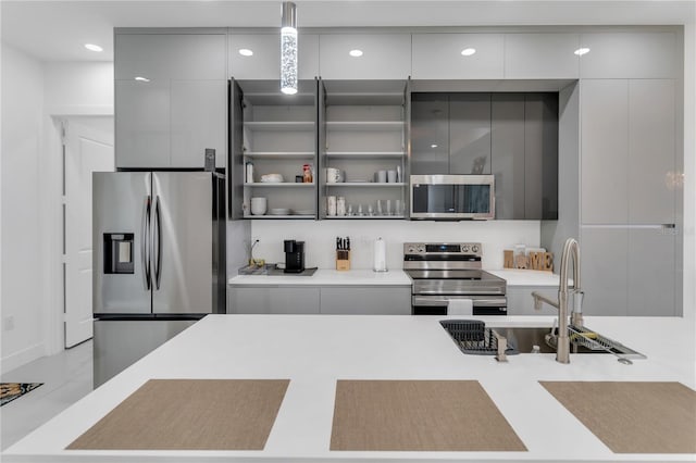 kitchen with appliances with stainless steel finishes, sink, hanging light fixtures, and gray cabinetry