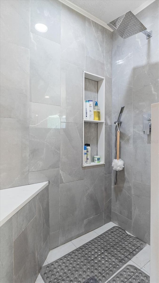 bathroom featuring tile patterned flooring, tiled shower, and crown molding