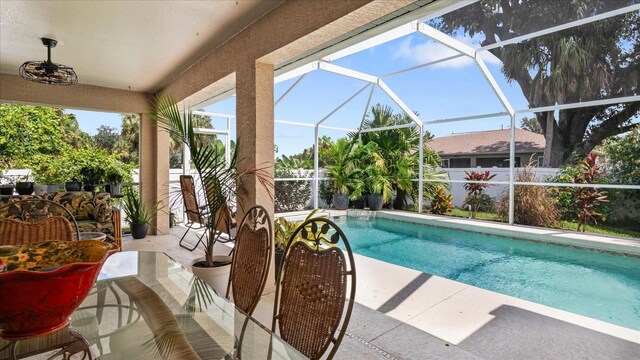 view of swimming pool with ceiling fan, a lanai, and a patio