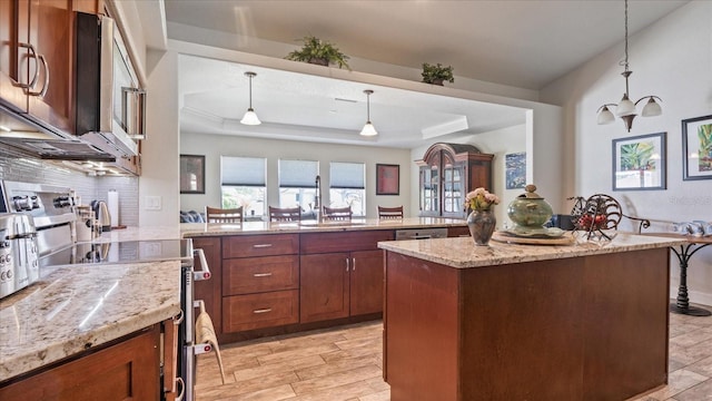 kitchen featuring stainless steel appliances, sink, decorative light fixtures, light hardwood / wood-style flooring, and a kitchen island