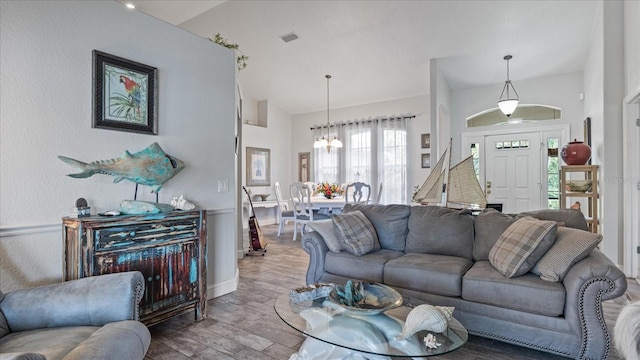 living room featuring a notable chandelier, wood-type flooring, and vaulted ceiling