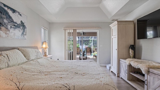 bedroom with a textured ceiling, access to outside, multiple windows, and dark hardwood / wood-style floors