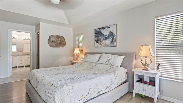 bedroom with multiple windows, hardwood / wood-style flooring, and connected bathroom