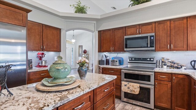 kitchen featuring tasteful backsplash, light hardwood / wood-style flooring, light stone countertops, and appliances with stainless steel finishes