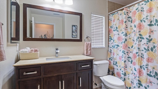 bathroom featuring walk in shower, vanity, and toilet