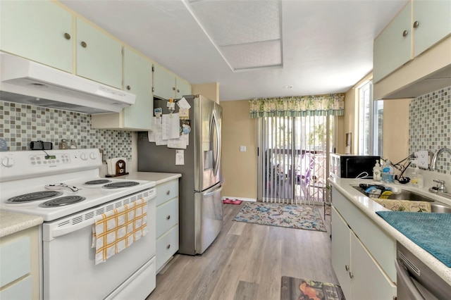 kitchen with appliances with stainless steel finishes, decorative backsplash, light wood-type flooring, and sink