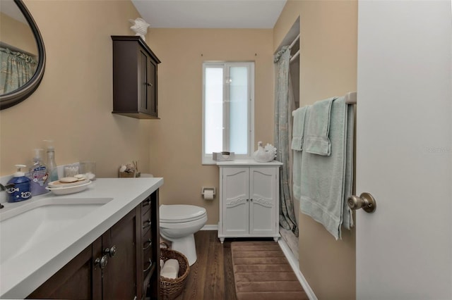 bathroom with hardwood / wood-style floors, walk in shower, vanity, and toilet