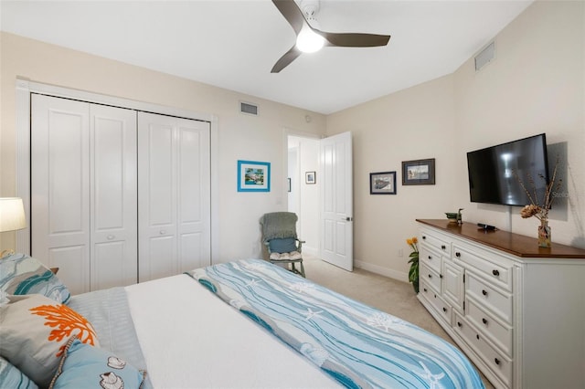 bedroom with ceiling fan, light carpet, and a closet