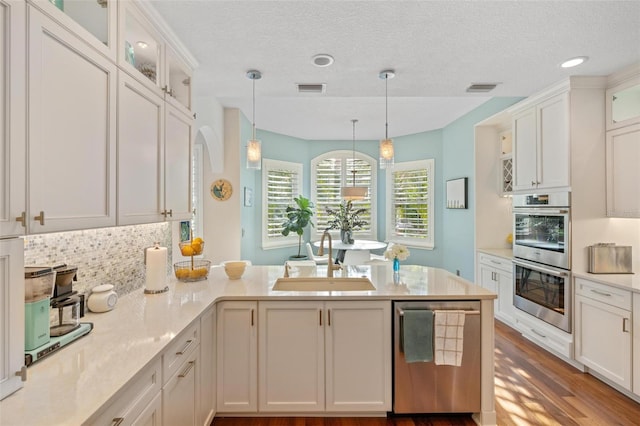 kitchen with white cabinets, appliances with stainless steel finishes, decorative light fixtures, and sink