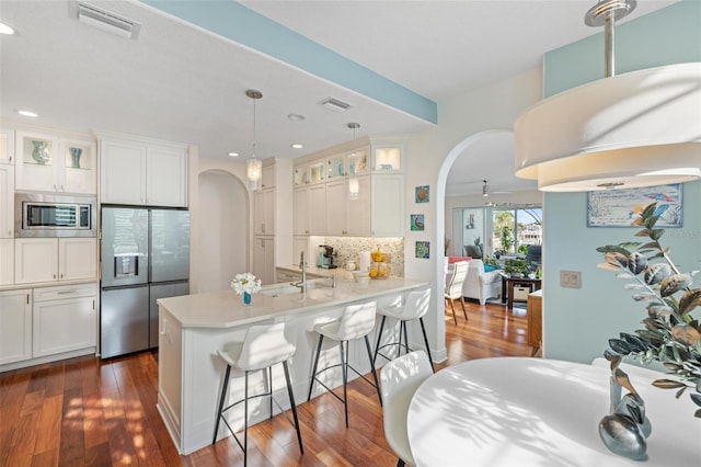 kitchen featuring appliances with stainless steel finishes, hanging light fixtures, dark hardwood / wood-style flooring, and white cabinets