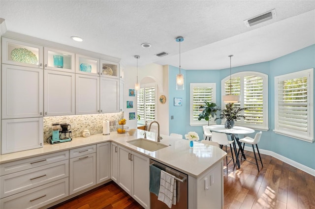 kitchen featuring dishwasher, sink, kitchen peninsula, and white cabinetry