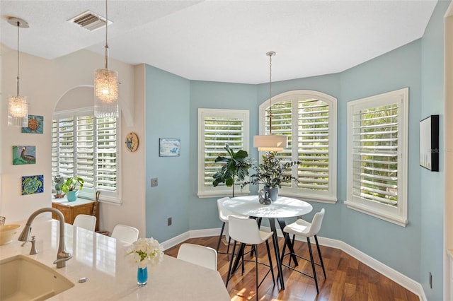 dining space featuring a textured ceiling, wood-type flooring, and sink