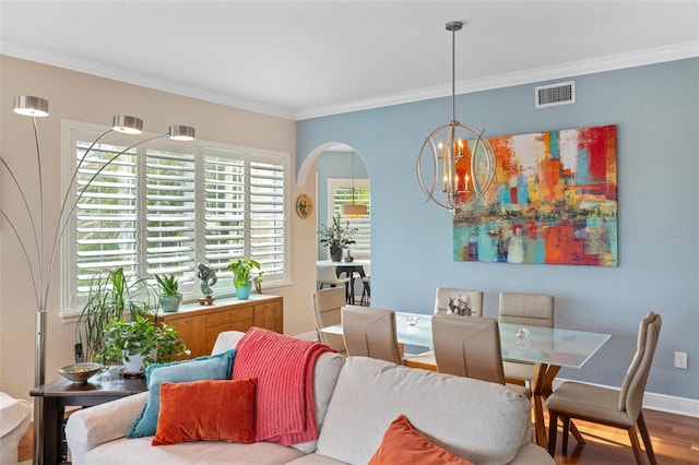 dining room with ornamental molding, an inviting chandelier, and hardwood / wood-style floors