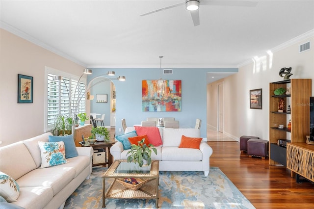 living room featuring ceiling fan with notable chandelier, wood-type flooring, and ornamental molding