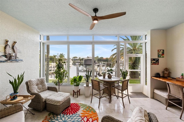 sunroom featuring ceiling fan, a water view, and a wealth of natural light