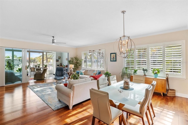 dining room with ornamental molding, ceiling fan with notable chandelier, light hardwood / wood-style floors, and a wealth of natural light