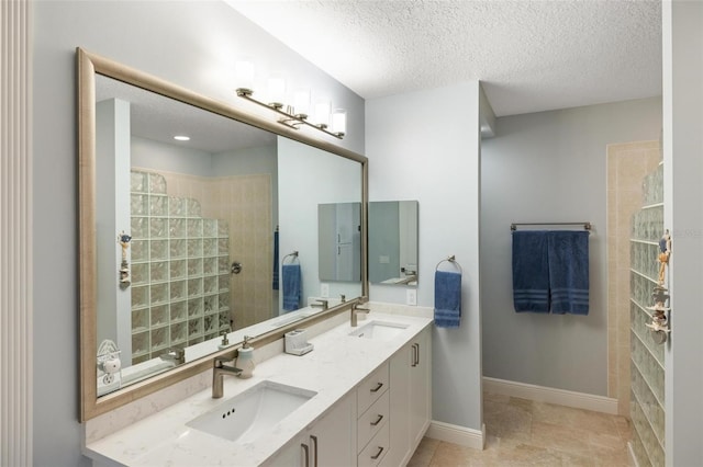 bathroom featuring a textured ceiling, vanity, and tiled shower