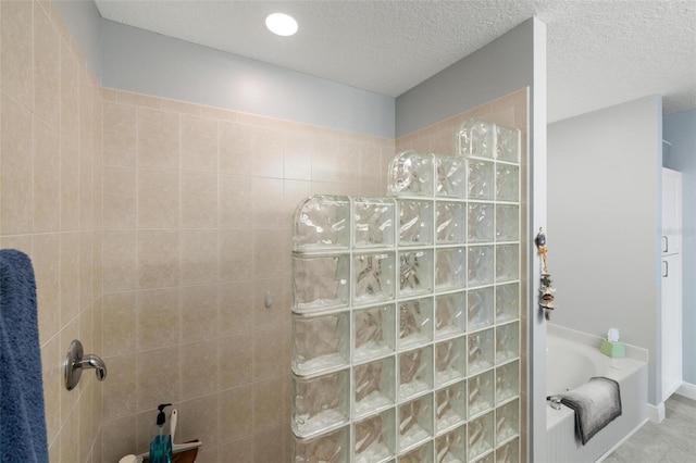 bathroom with a textured ceiling, tile walls, plus walk in shower, and tile patterned floors