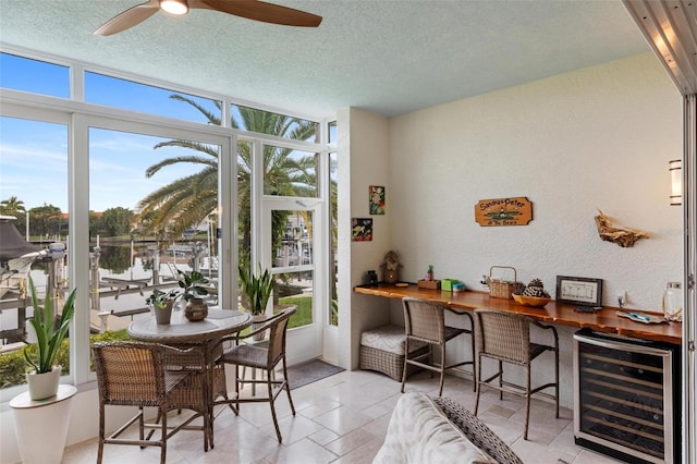 interior space with a water view, wine cooler, ceiling fan, and a textured ceiling