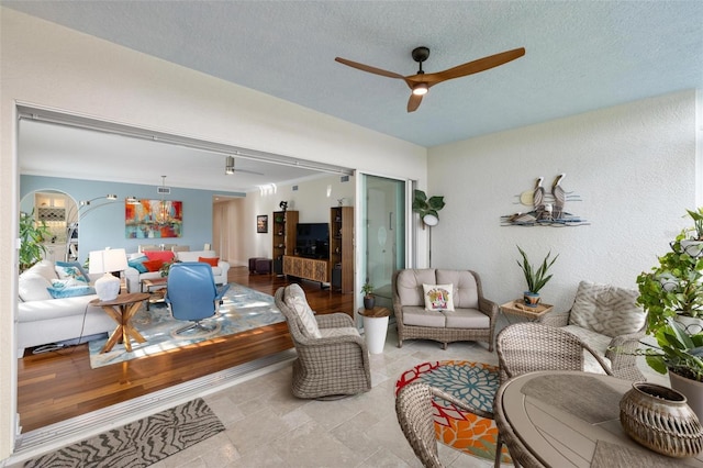 living room with a textured ceiling and ceiling fan