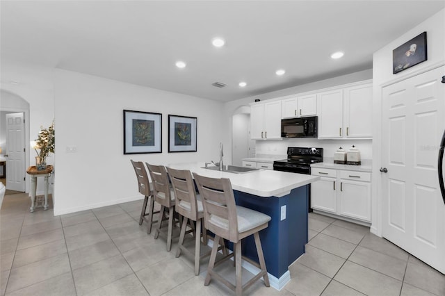 kitchen featuring a kitchen island with sink, sink, white cabinetry, a kitchen bar, and black appliances