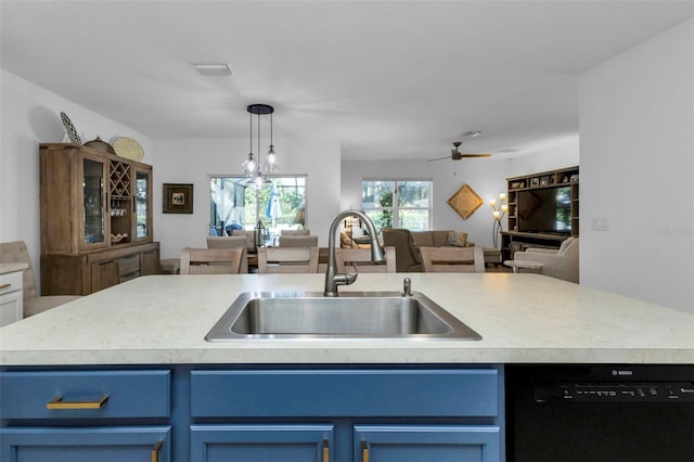 kitchen with black dishwasher, sink, ceiling fan with notable chandelier, a center island with sink, and blue cabinets