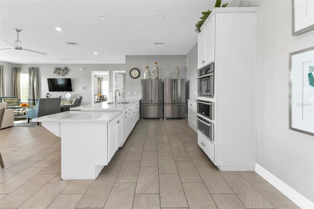 kitchen with stainless steel appliances, white cabinetry, ceiling fan, and sink