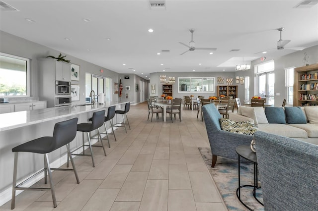 living room with ceiling fan with notable chandelier and sink