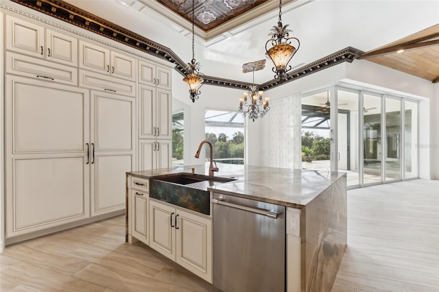 kitchen with pendant lighting, an island with sink, sink, stainless steel dishwasher, and cream cabinets