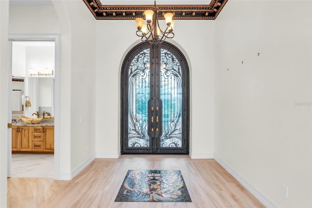 foyer entrance with an inviting chandelier, light hardwood / wood-style floors, and french doors