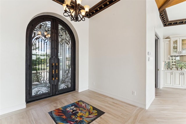 foyer with a chandelier, beamed ceiling, high vaulted ceiling, light hardwood / wood-style flooring, and french doors