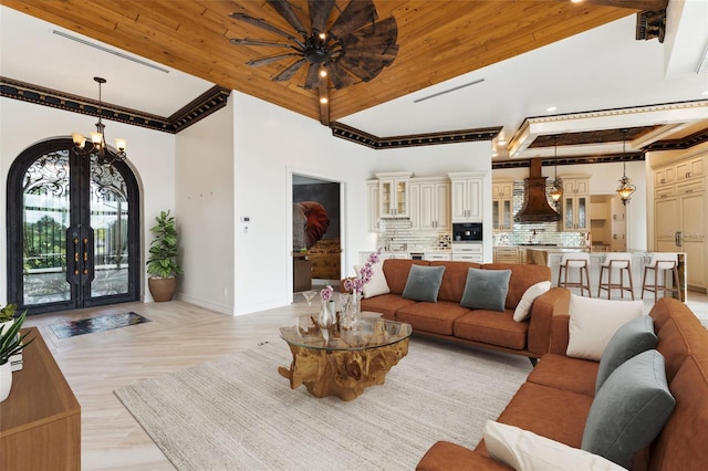 living room with french doors, beamed ceiling, ceiling fan with notable chandelier, and light hardwood / wood-style floors