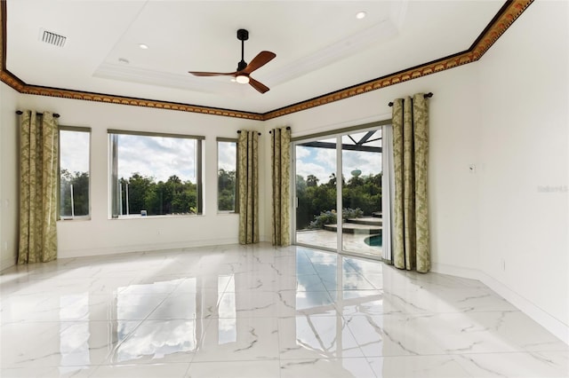 empty room with ceiling fan, a raised ceiling, and crown molding