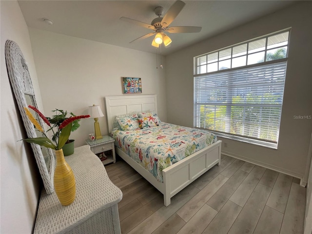 bedroom featuring ceiling fan, light hardwood / wood-style flooring, and multiple windows