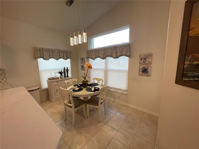 dining space featuring a notable chandelier, light tile patterned flooring, and vaulted ceiling