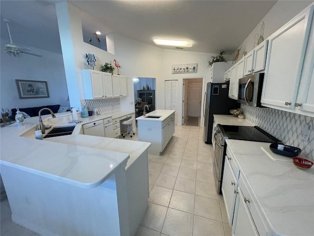 kitchen with vaulted ceiling, white cabinets, kitchen peninsula, stainless steel appliances, and sink