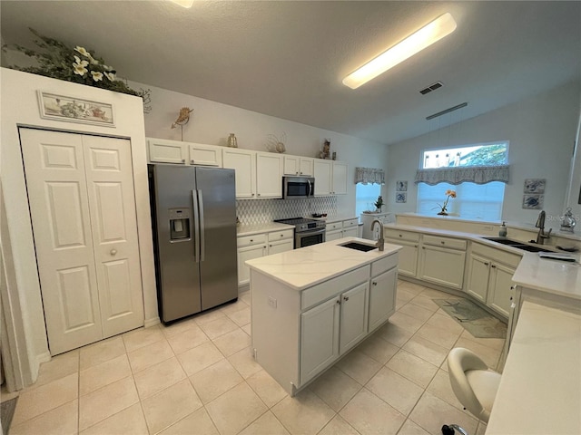 kitchen featuring white cabinetry, stainless steel appliances, lofted ceiling, a center island, and sink